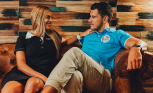 Dame und Herr tragen figurbetonte Nebulus Poloshirts auf einer Ledercouch