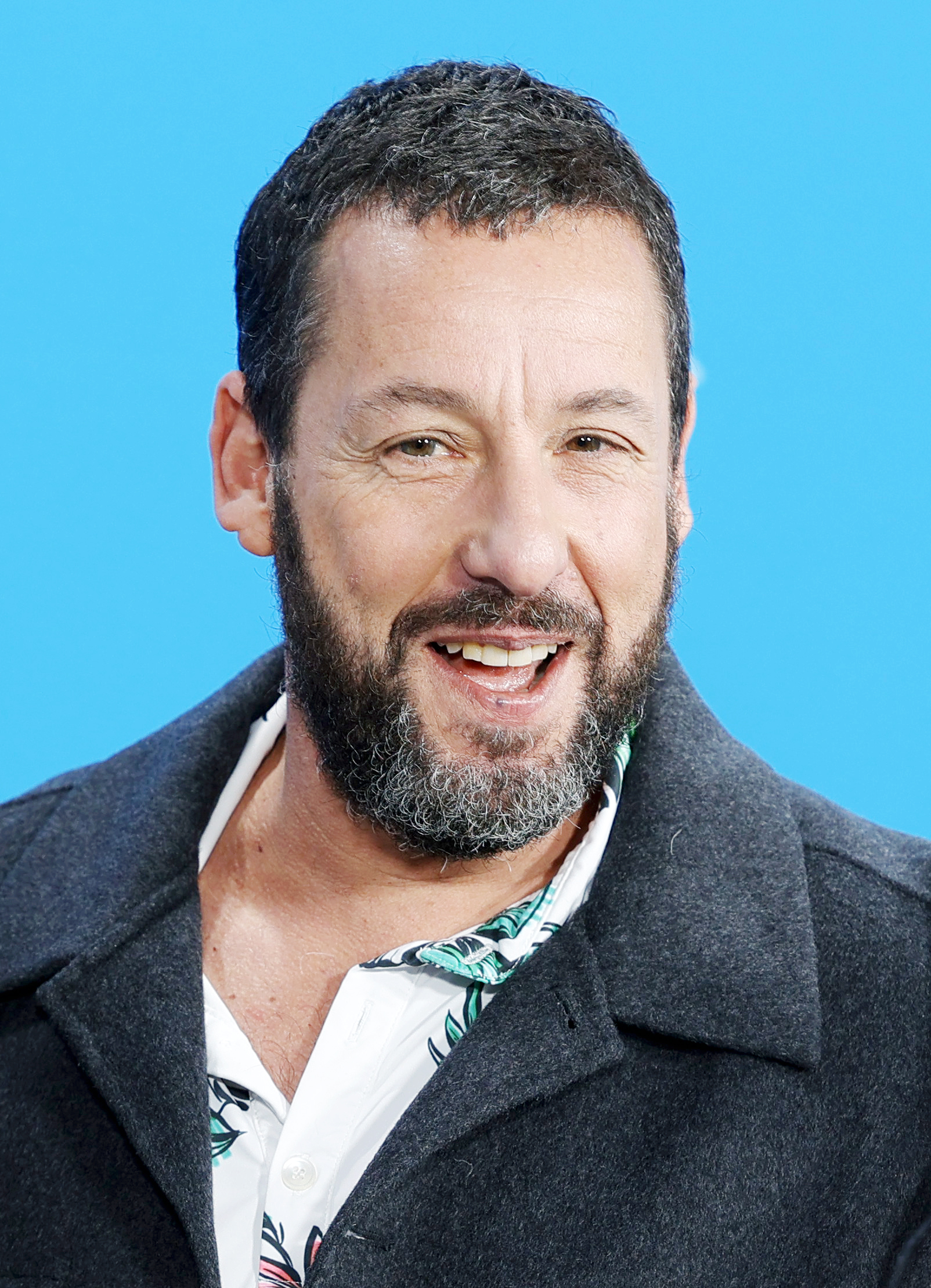 Adam Sandler bei einem öffentlichen Auftritt 2024 mit Bart und dunklem Mantel – Porträtaufnahme vor blauem Hintergrund Von Elena Ternovaja - Eigenes Werk, CC BY-SA 3.0, Link