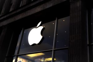 Apple Store mit leuchtendem Apple Logo an der Glasfassade