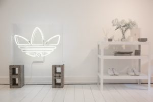 Adidas Trefoil Logo als Neonleuchte in modernem Raum mit Sneakern