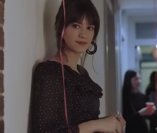 Szene aus „Normal People“: Marianne lehnt bei einer Party an der Wand, trägt ein schwarzes Kleid mit Punkten.